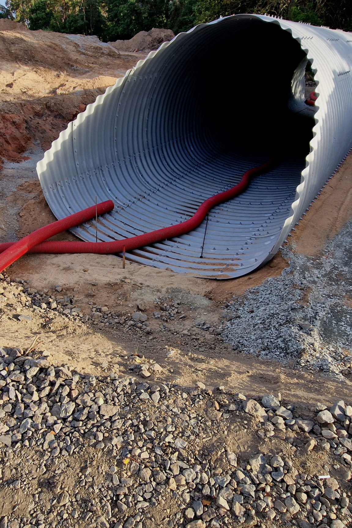 A corrugated iron tunnel will serve as a bridge over a stream under the road. Instant quick solution made of metal screwed pipe from parts. Bomb and missile shelter for civilians is being built
